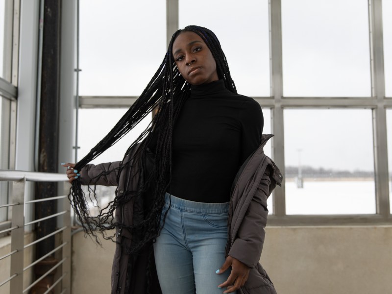 An activist Naira poses for a photo, holding her braids.