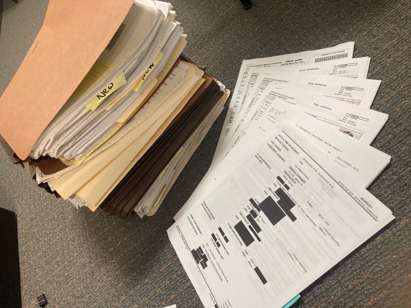 A stack of file folders next to partially-redacted papers fanned out on the floor.